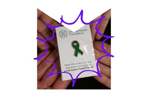 Green ribbon pin badge in an M-shaped frame