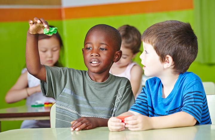 Children playing together, sat at desks