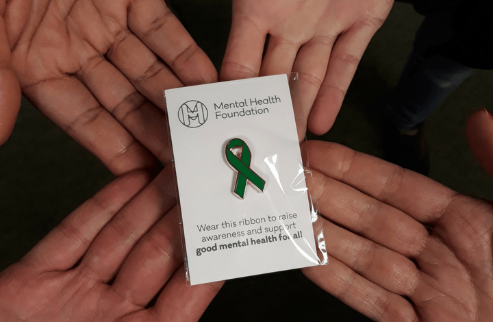 Green ribbon pin badge hands