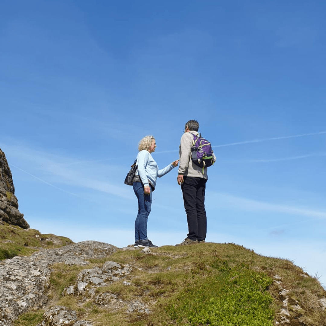 Two adults outdoors hiking, blue skies. 