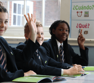 Pupils sat in a classroom, with their hands raised