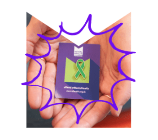 Someone holding a green ribbon pin badge