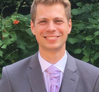 Photo of Michael Hough wearing a suit and smiling at the camera