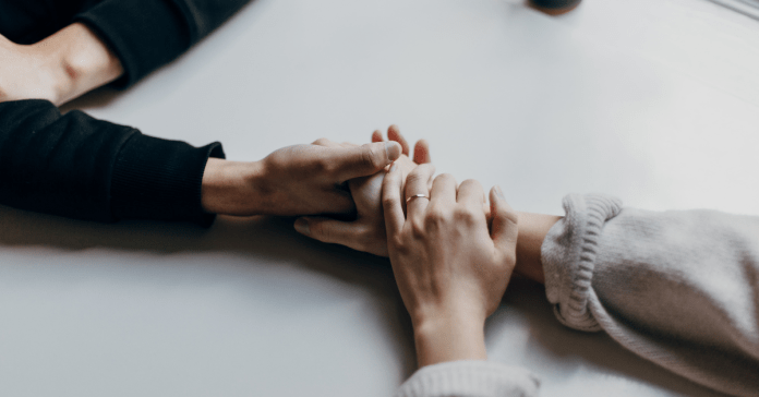 Two people holding hands over a table