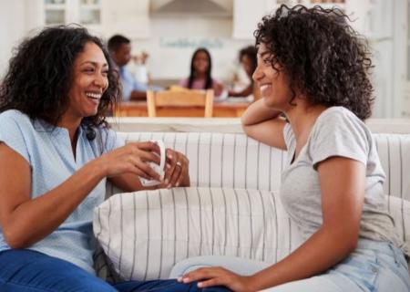 Two women sat on a sofa talking together