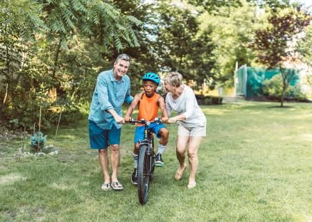 Photo of parents teaching son to ride a bike