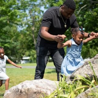 Photo of a father and his two daughters playing in nature